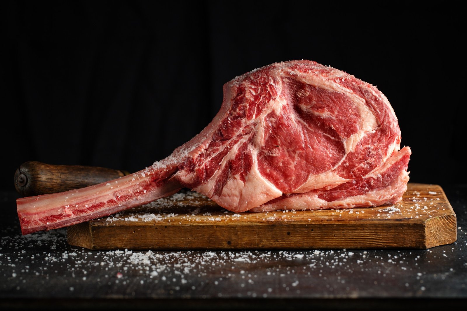Home fresh meat tomahawk steak on old wooden board. dark background. closeup
